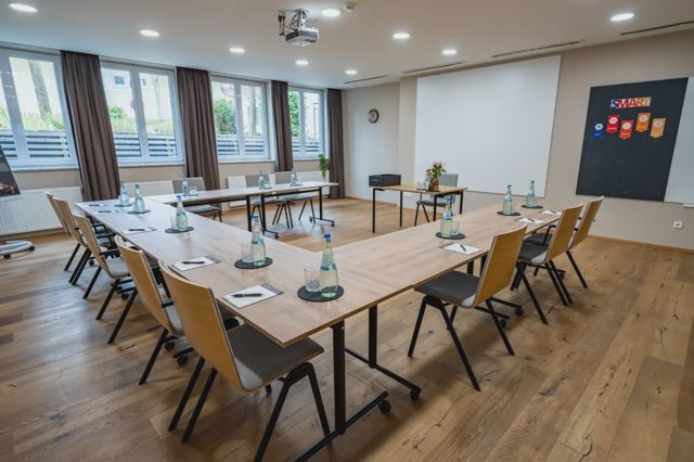 Tagungsraum mit Tischen in U-Form und Beamer