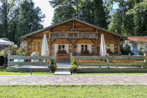 Die Chiemseer-Alm: Blockhütte mit Holzbalkon, Geranien und Terrasse mit Sonnenschirmen