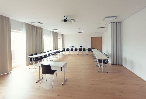 Konferenzraum in U-Form mit Eichendielen und Deckenbeamer, rechts die Faltwand zum Nachbarraum