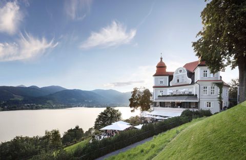 Das Sengerschloss über dem Tegernsee, davor die Terrasse mit Blick auf See und Berge