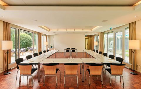 Parkseminarraum in U-Form bestuhlt, bodentiefe Fenster zum Garten