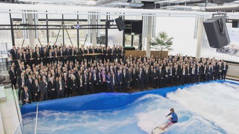 Firmenveranstaltung im Surfrotor: mehrere hundert Gäste am Beckenrand, auf der Indoor-Welle eine Surferin